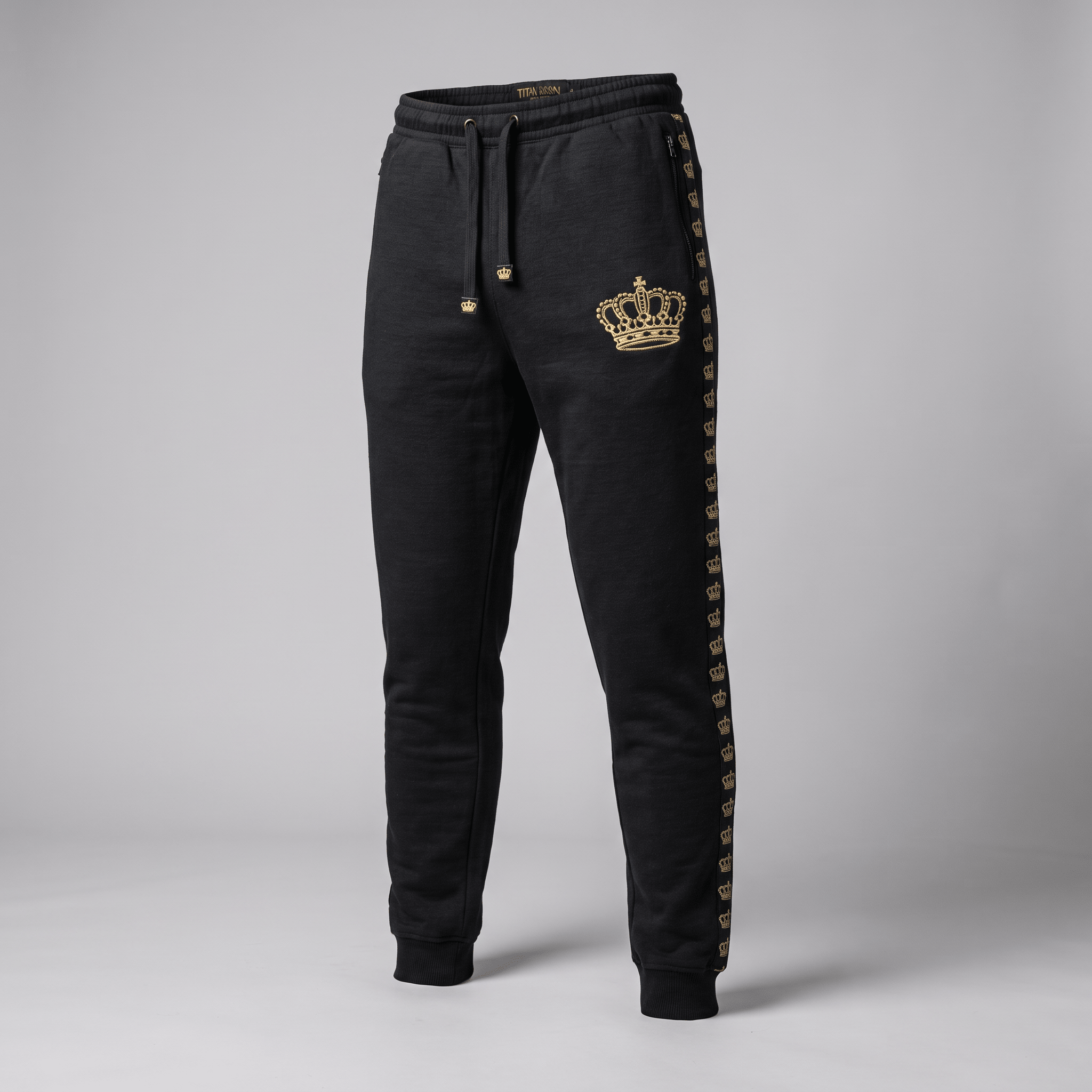 Black athletic joggers with a gold crown print on the left hip and a repeating gold crown side stripe.