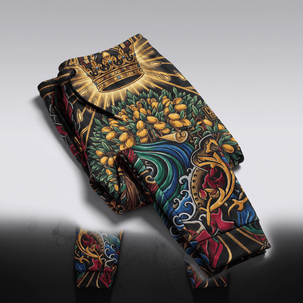 Folded black joggers featuring a vibrant baroque crown, fruit, and floral tattoo print pattern.