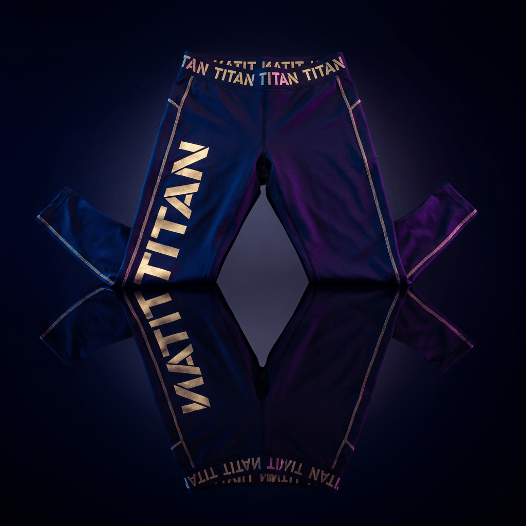 Black athletic leggings with gold "TITAN" branding on the thigh and waistband, set against a dark reflective surface.