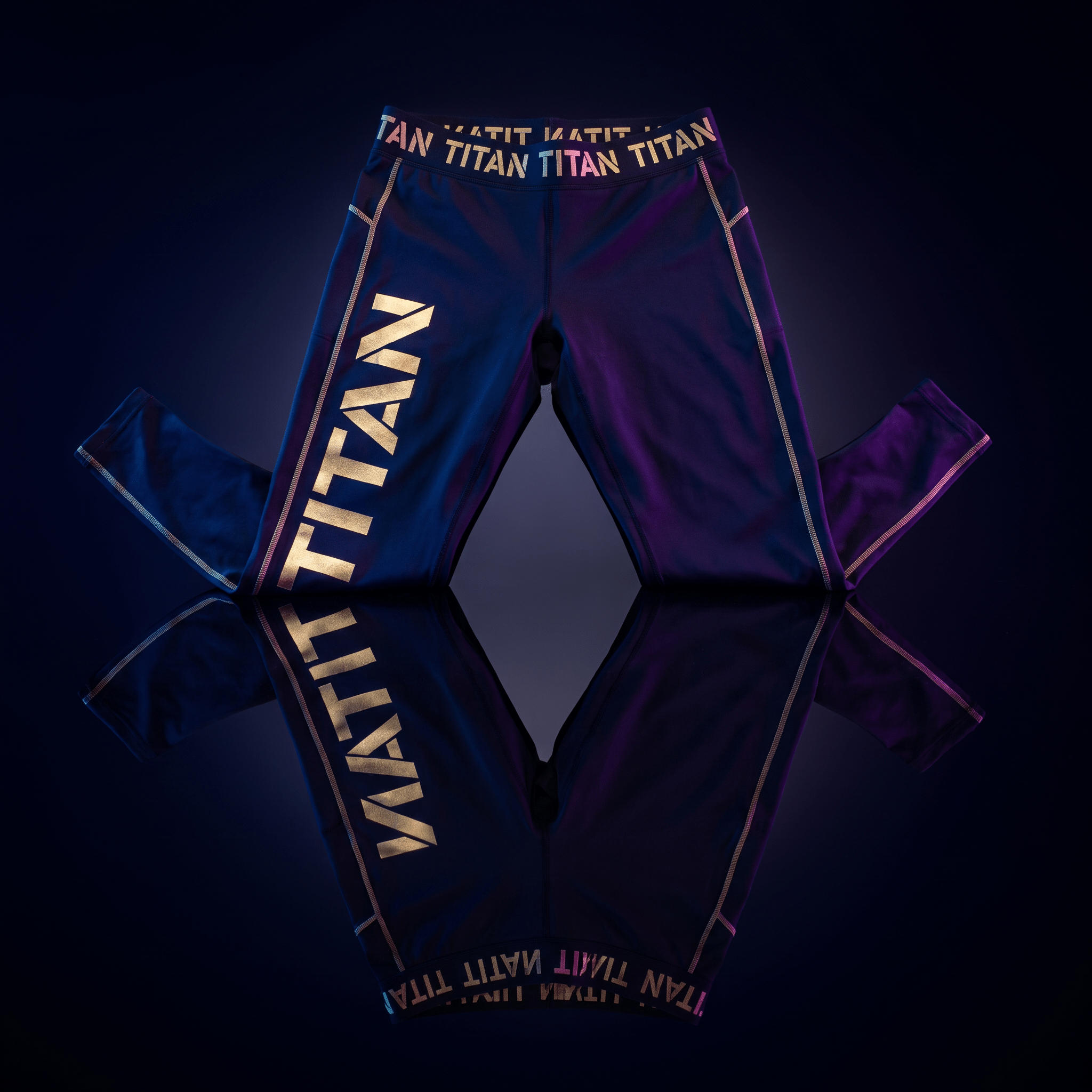 Black athletic leggings with gold "TITAN" branding on the thigh and waistband, set against a dark reflective surface.
