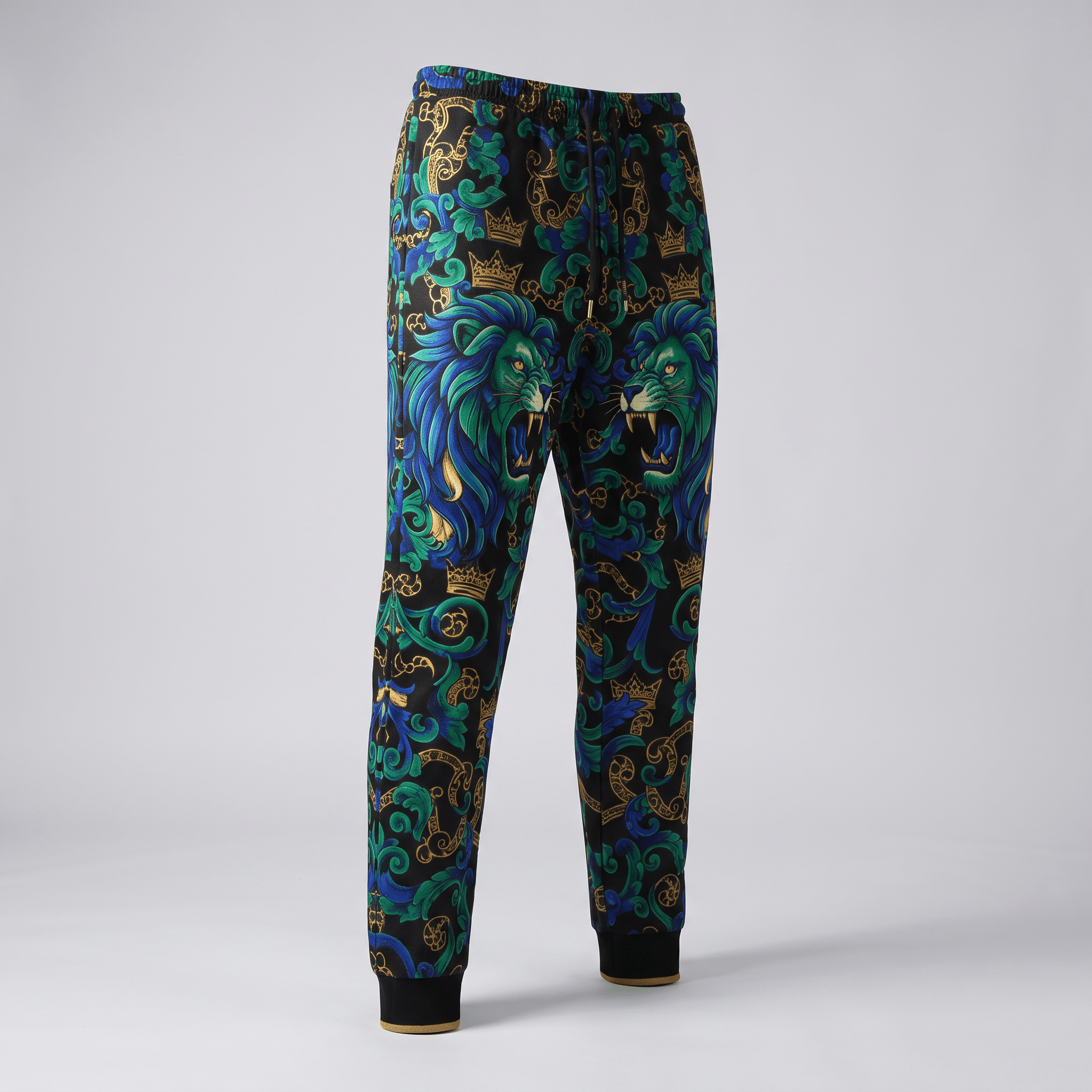 Black sweatpants featuring a blue and green lion print with gold baroque crowns and swirling scrollwork.