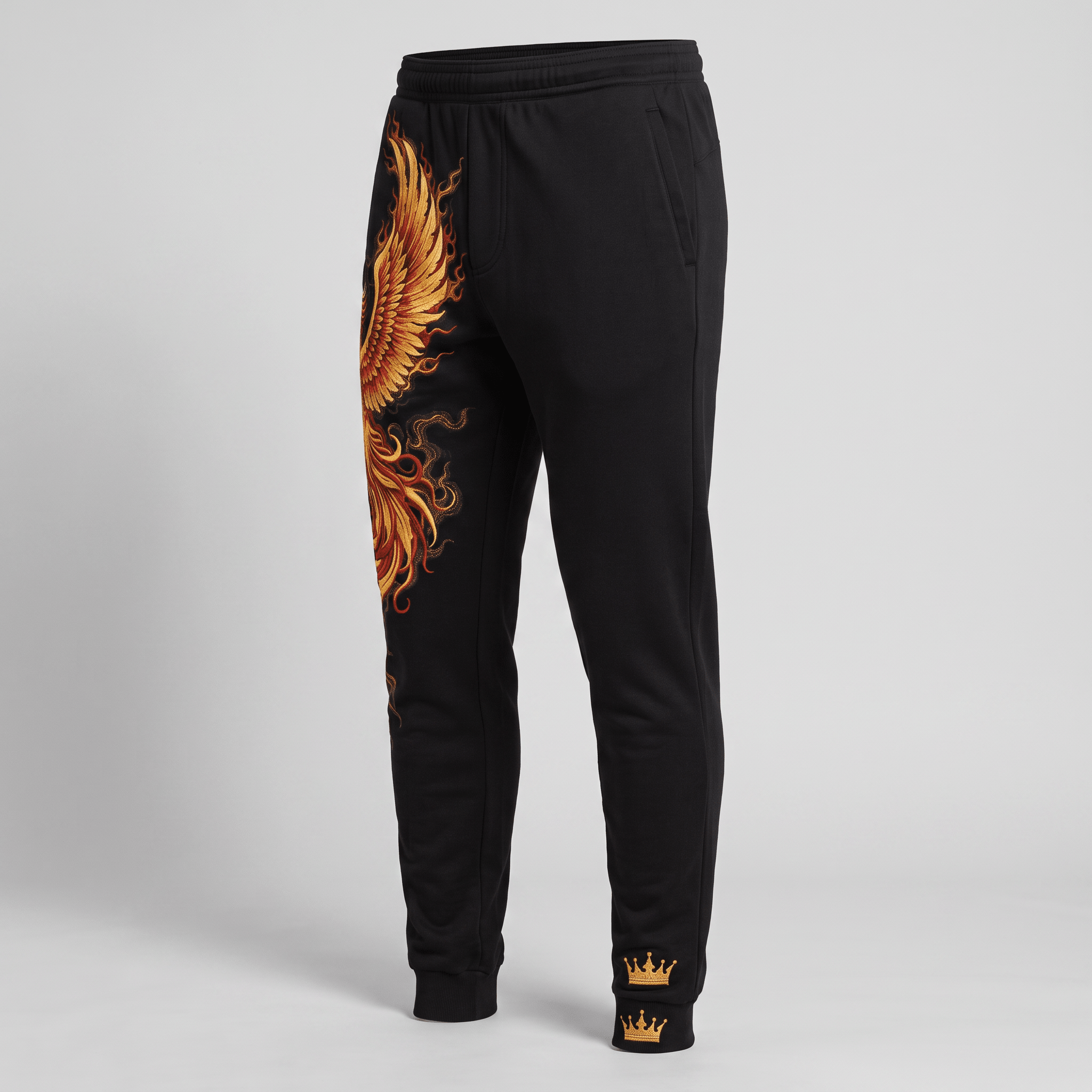 Black joggers with gold and orange phoenix wing graphic on the right leg and crown logo on the ankle.