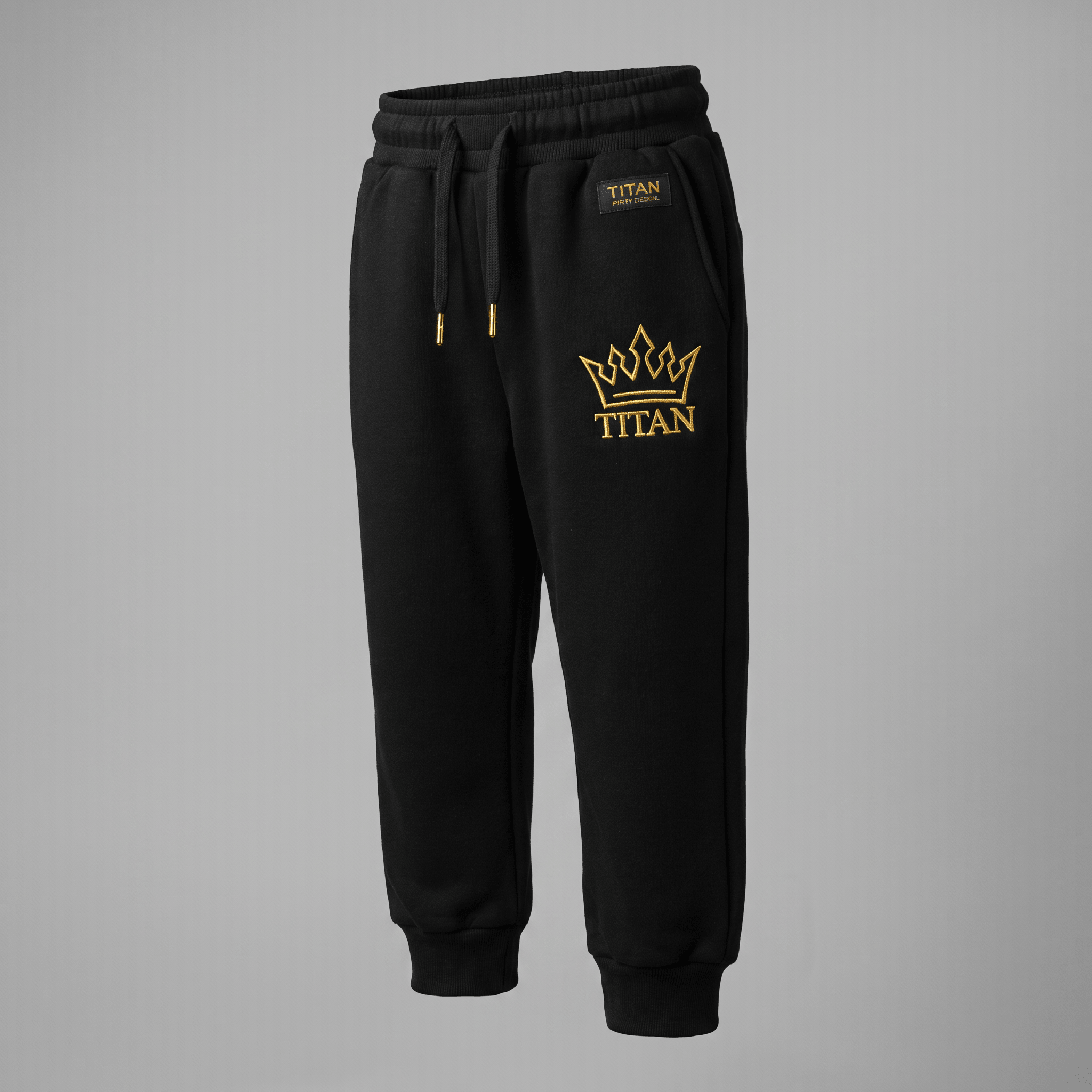 Black joggers with gold Titan crown embroidery and drawstring waist against a grey background.