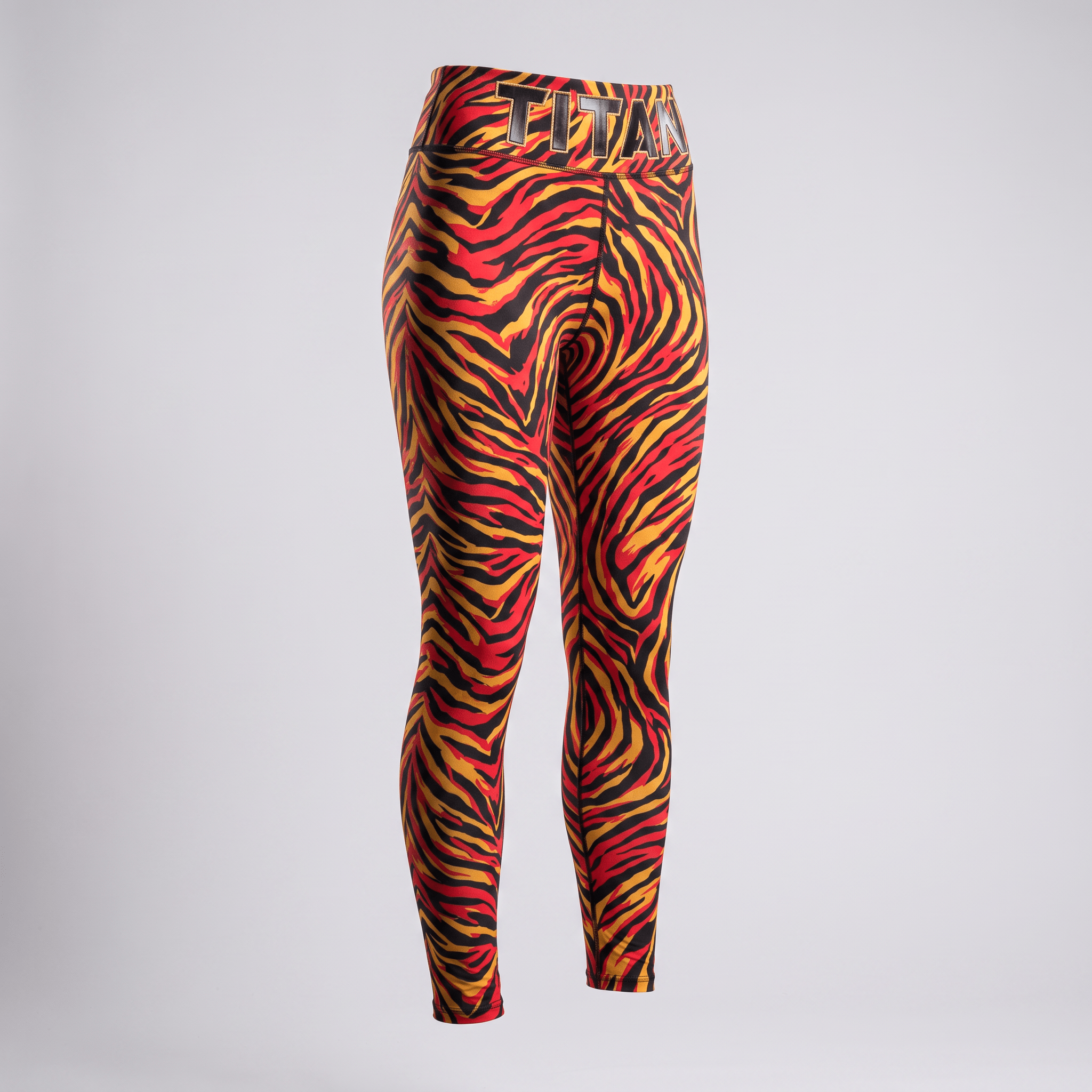 Red, yellow, and black animal print athletic leggings with Titan branded waistband on white.