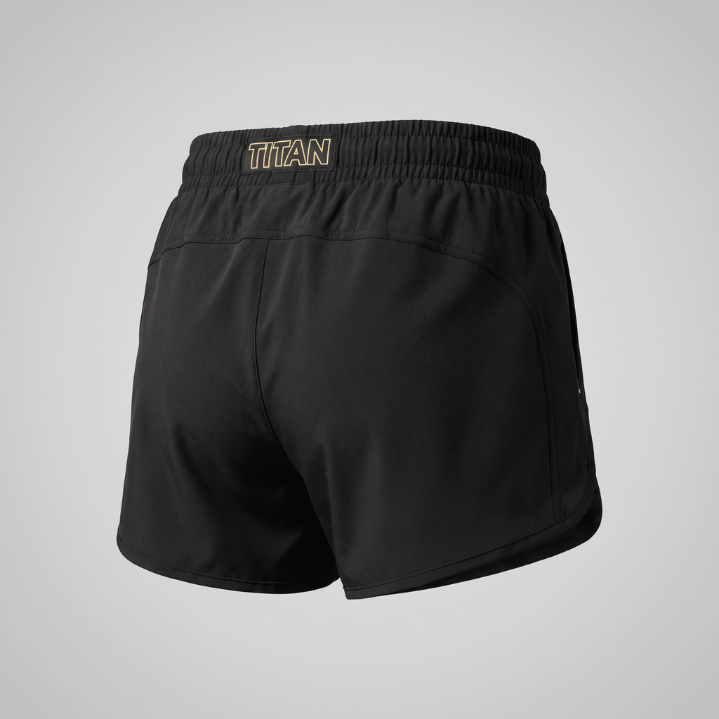 Back view of black athletic shorts with gold Titan logo on the elastic waistband, isolated on a light gray background.