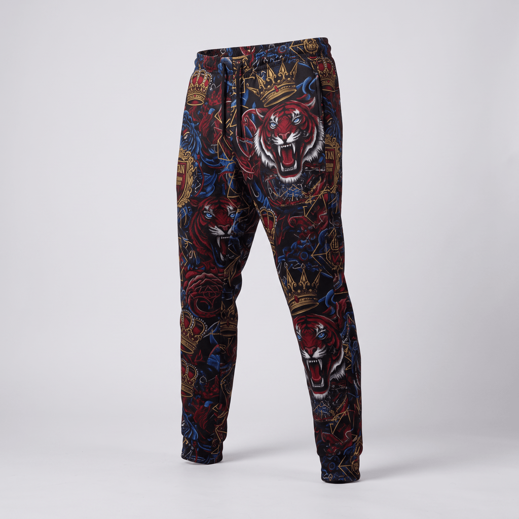 Black joggers with a vibrant all-over print featuring roaring tigers, crowns, and red roses on a light background.