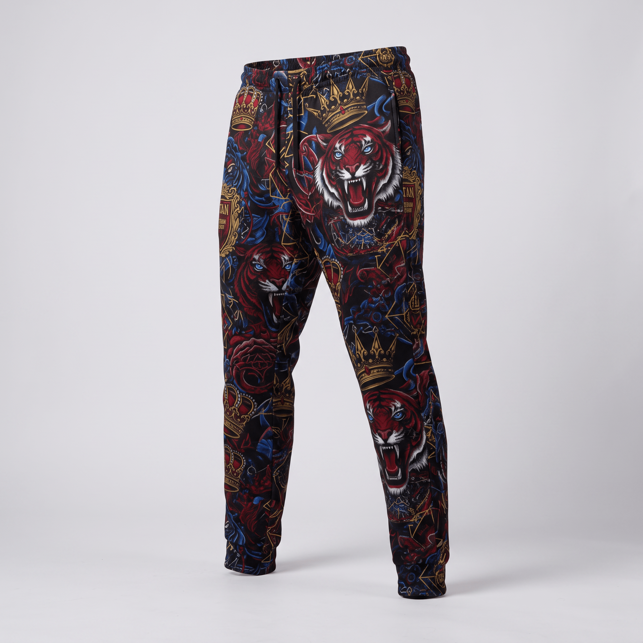 Black joggers featuring a bold red tiger, crown, and rose graphic print against a grey background.