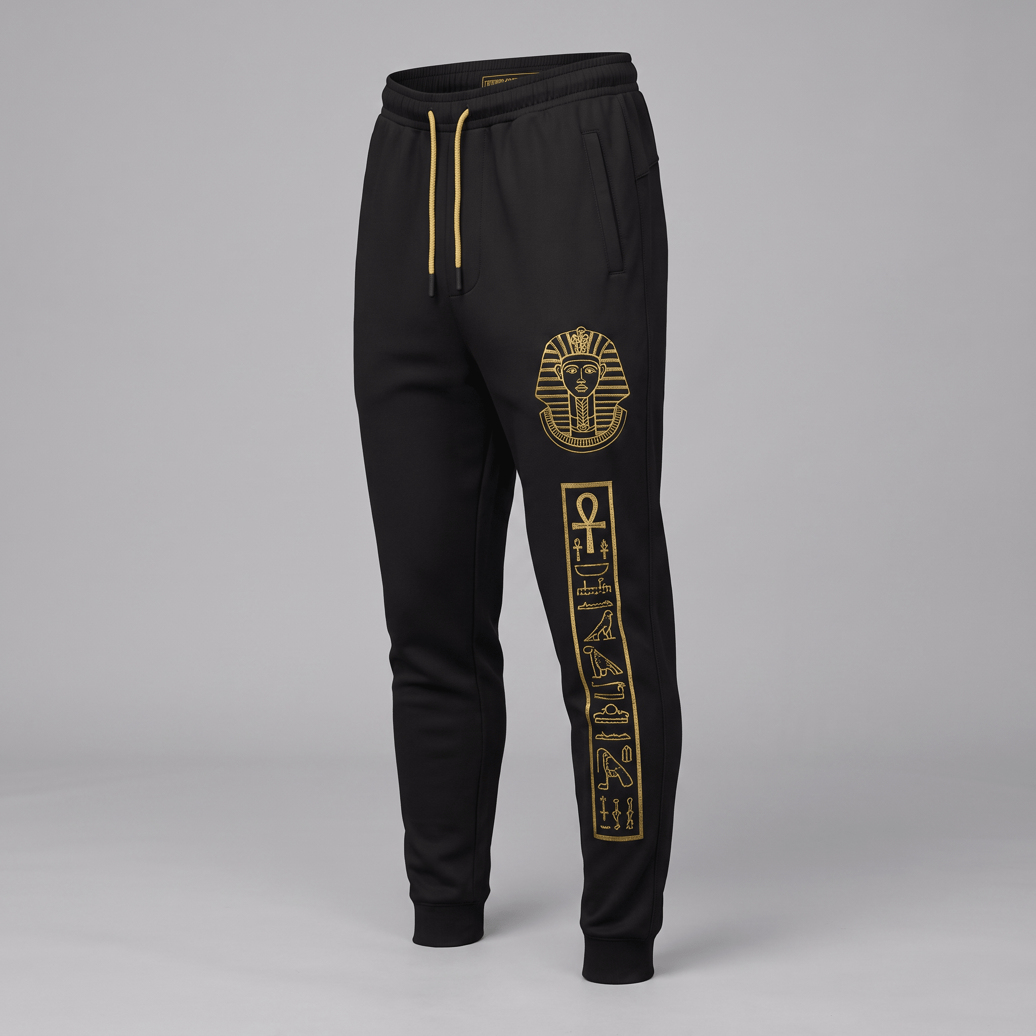 Black sweatpants with gold drawstring, pharaoh graphic, and hieroglyphic leg print.