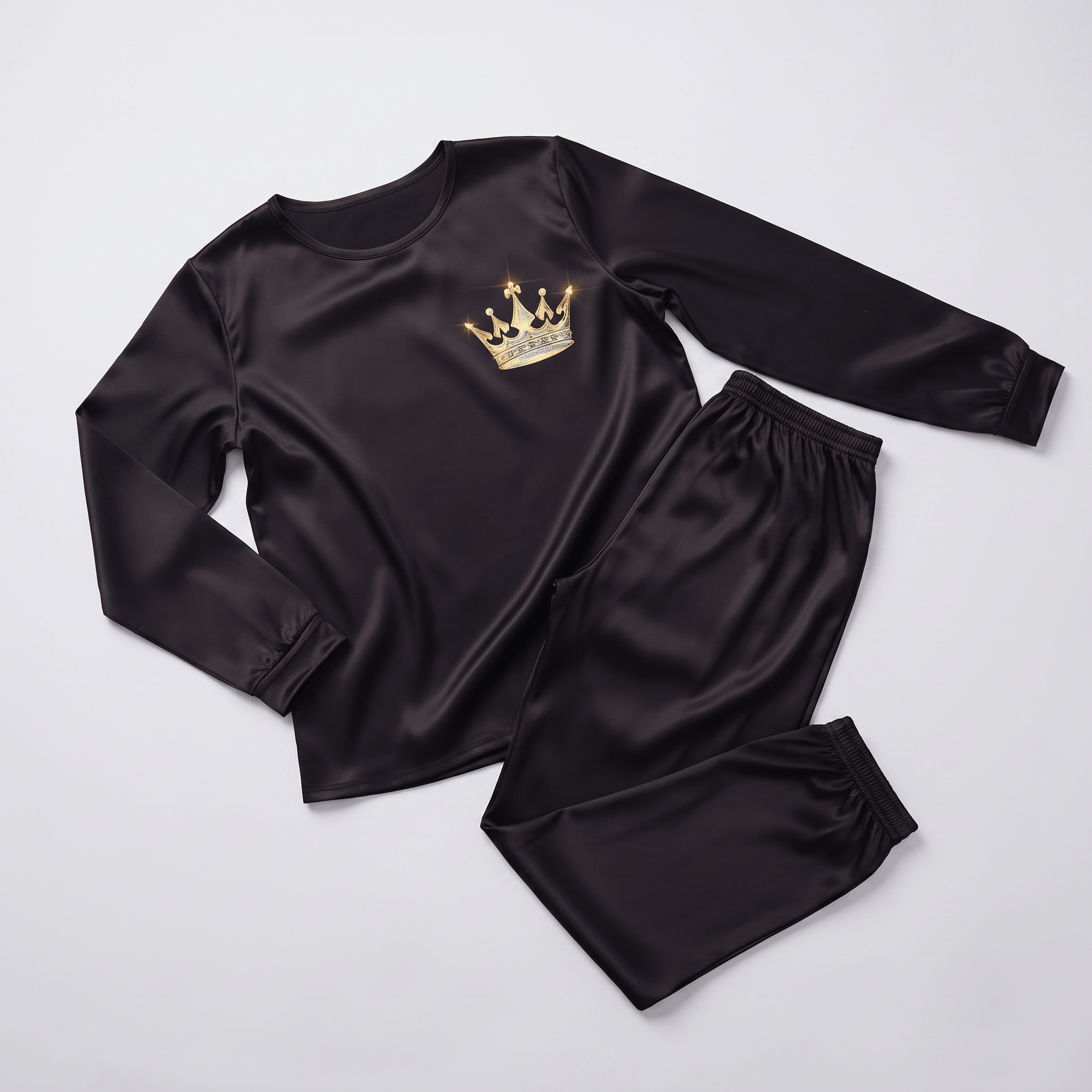 Black satin long-sleeve pajama set with a gold crown graphic on the chest, laid flat.