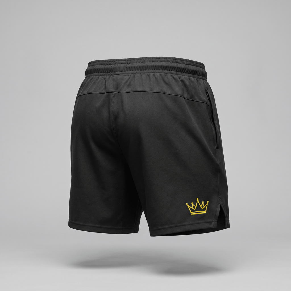 Back view of black athletic shorts featuring an elastic waistband and a small yellow crown logo on the lower left leg.