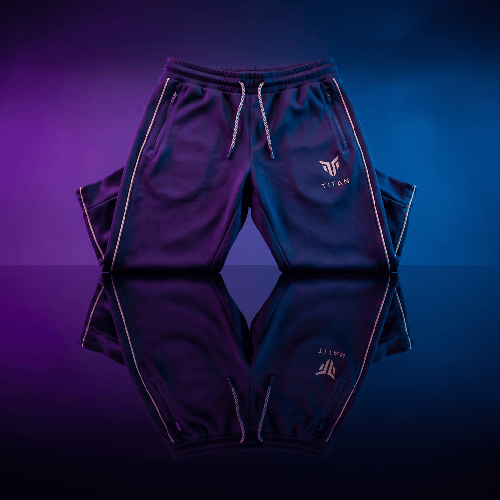 Dark blue Titan athletic joggers with gold piping and logo, featuring drawstring waist, set against neon lighting.
