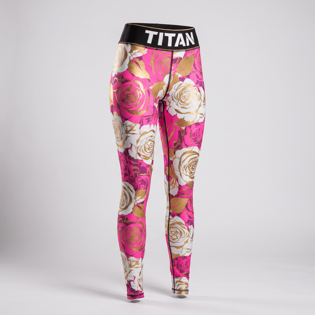 Titan pink athletic leggings featuring a gold and white rose floral print and a black branded waistband.