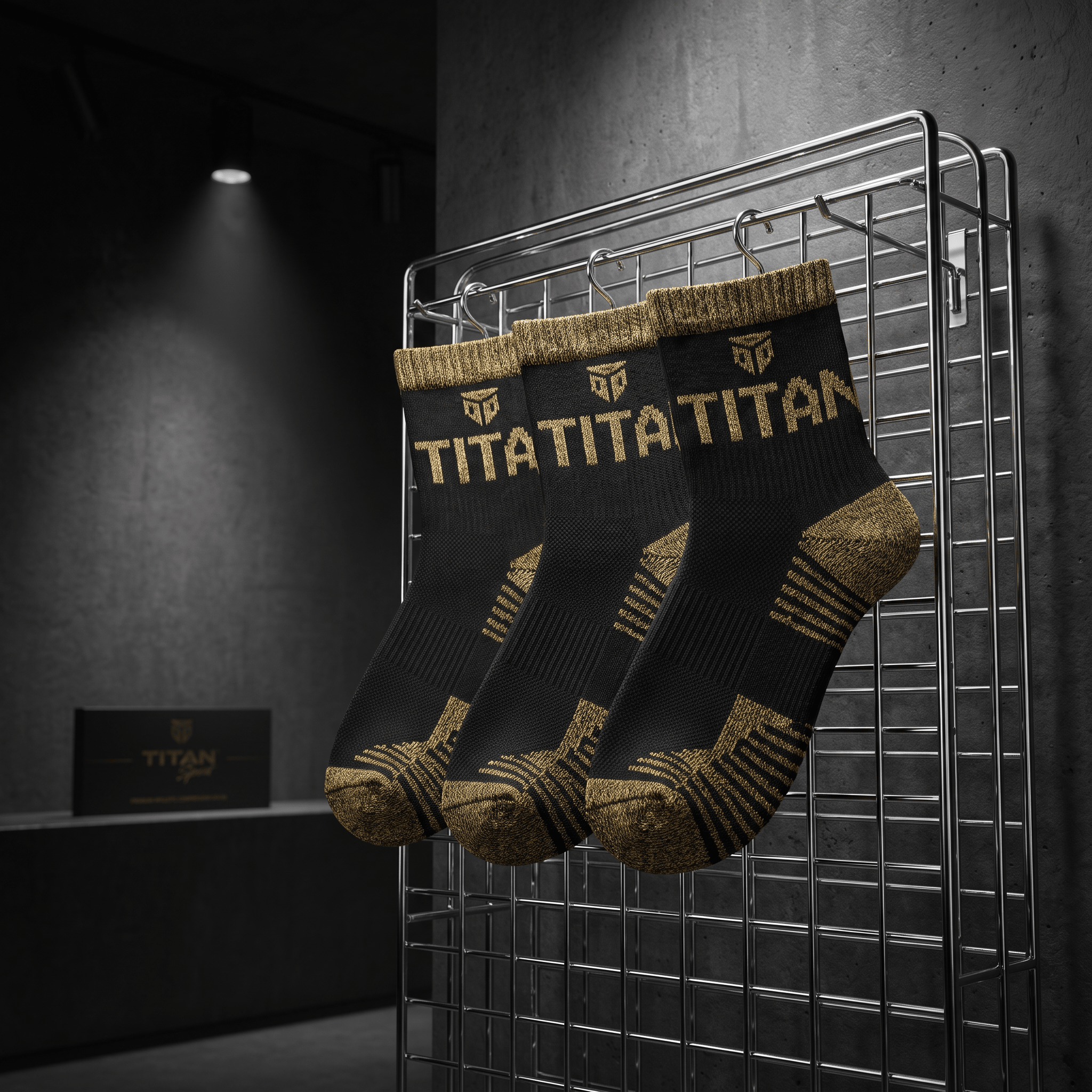 Three black athletic socks with gold "TITAN" branding and gold accents on heels and toes, hanging on a metal rack.