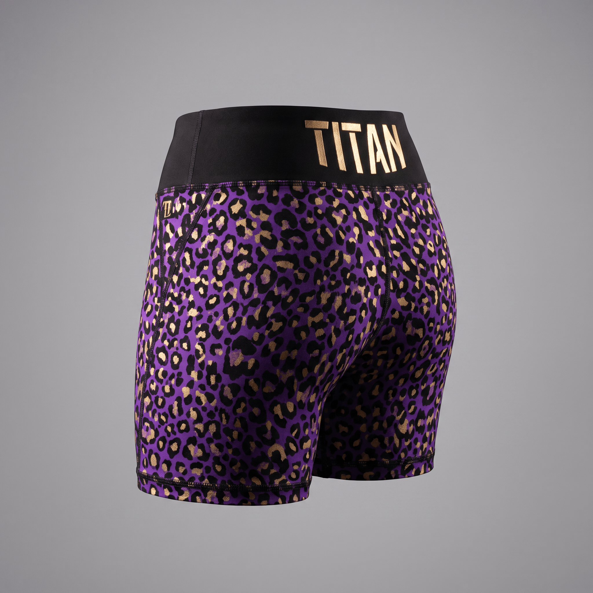 Rear view of purple and black leopard print athletic shorts featuring a wide black waistband with gold Titan logo.