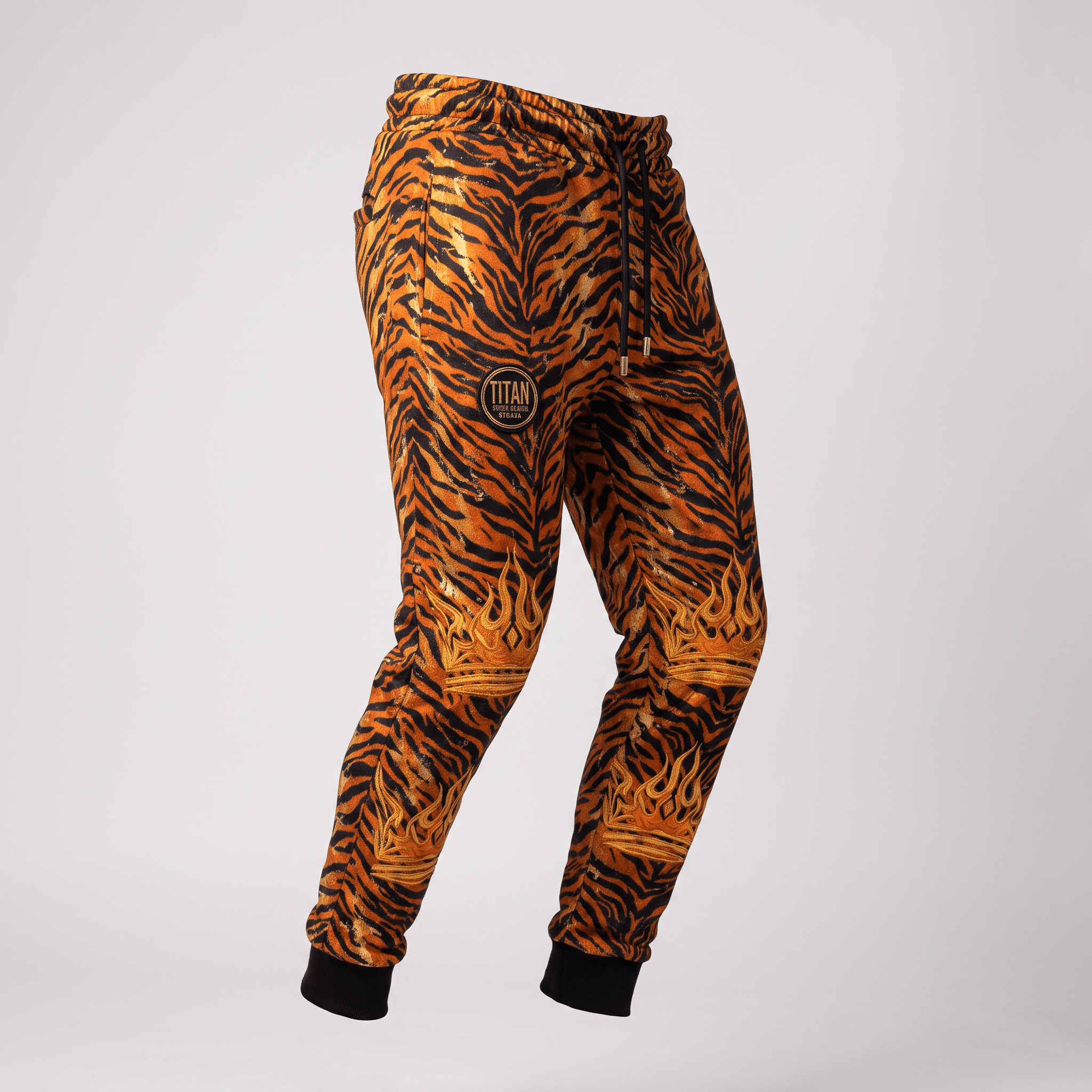 Orange and black tiger print joggers with black cuffs, drawstring waist, and gold crown graphics.