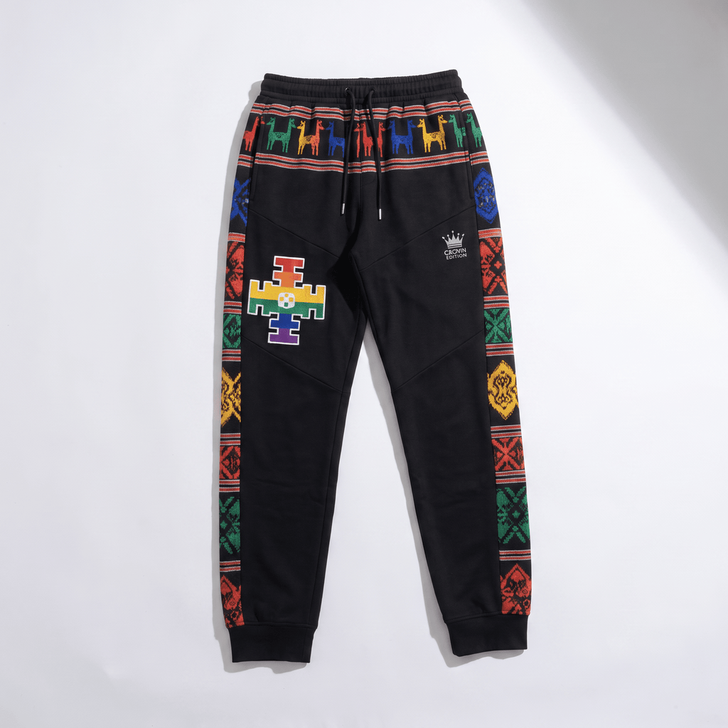 Black sweatpants with colorful patterned side stripes, a waistband llama print, and a rainbow cross patch.