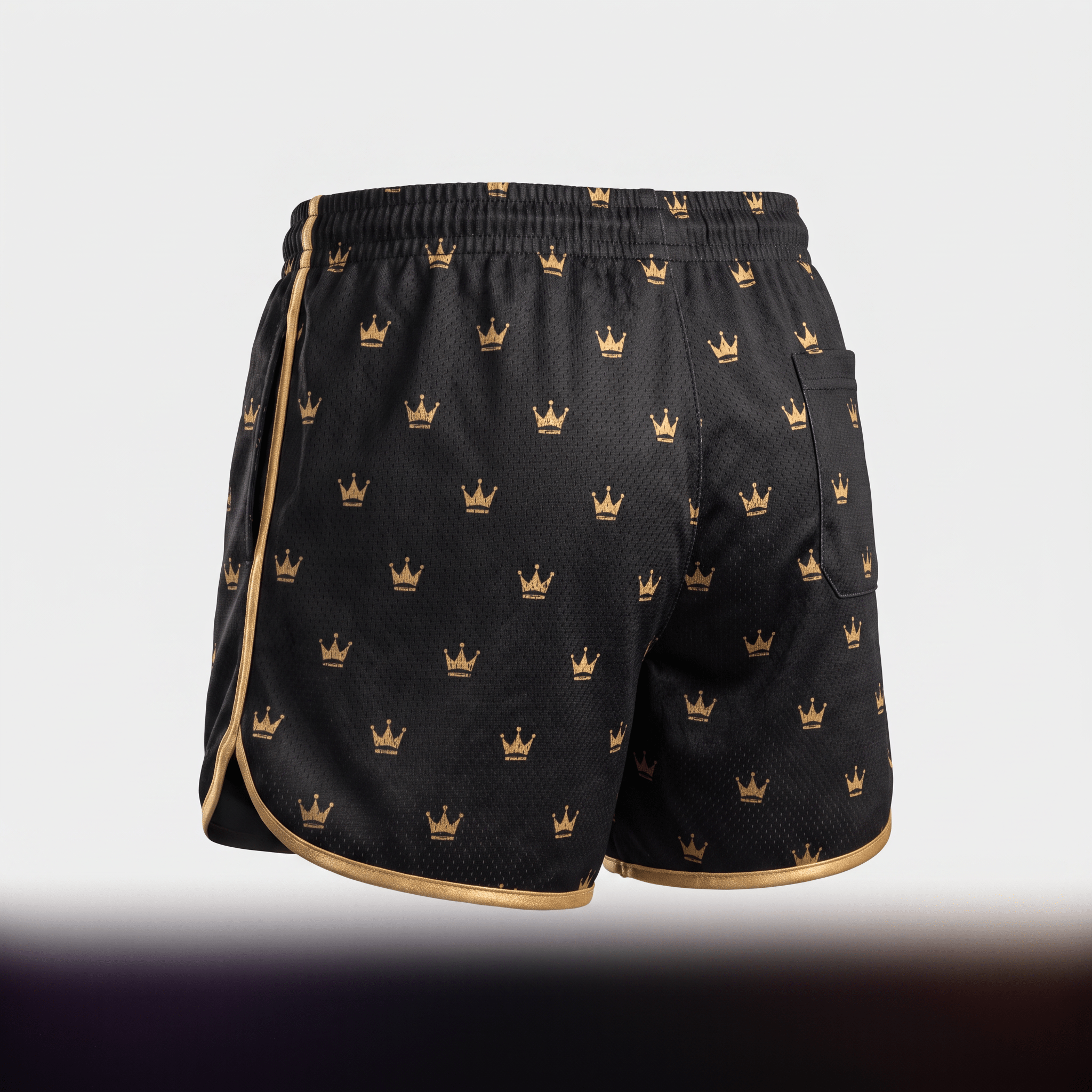 Back view of black athletic shorts with all-over gold crown pattern and gold trim on a white background.