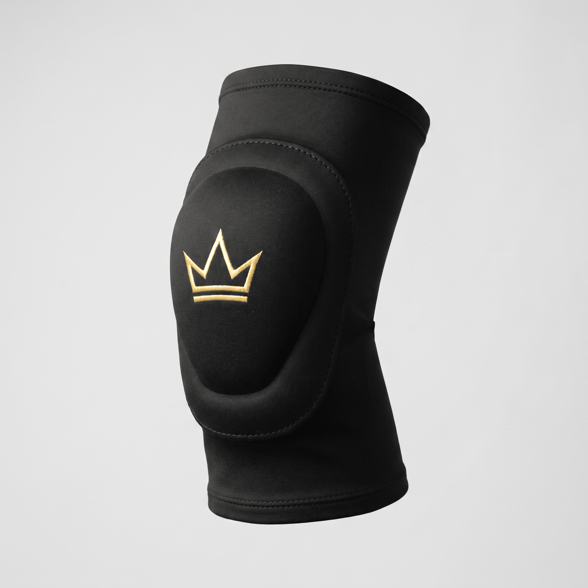 Black athletic knee pad with thick padding and embroidered gold crown logo on grey background.