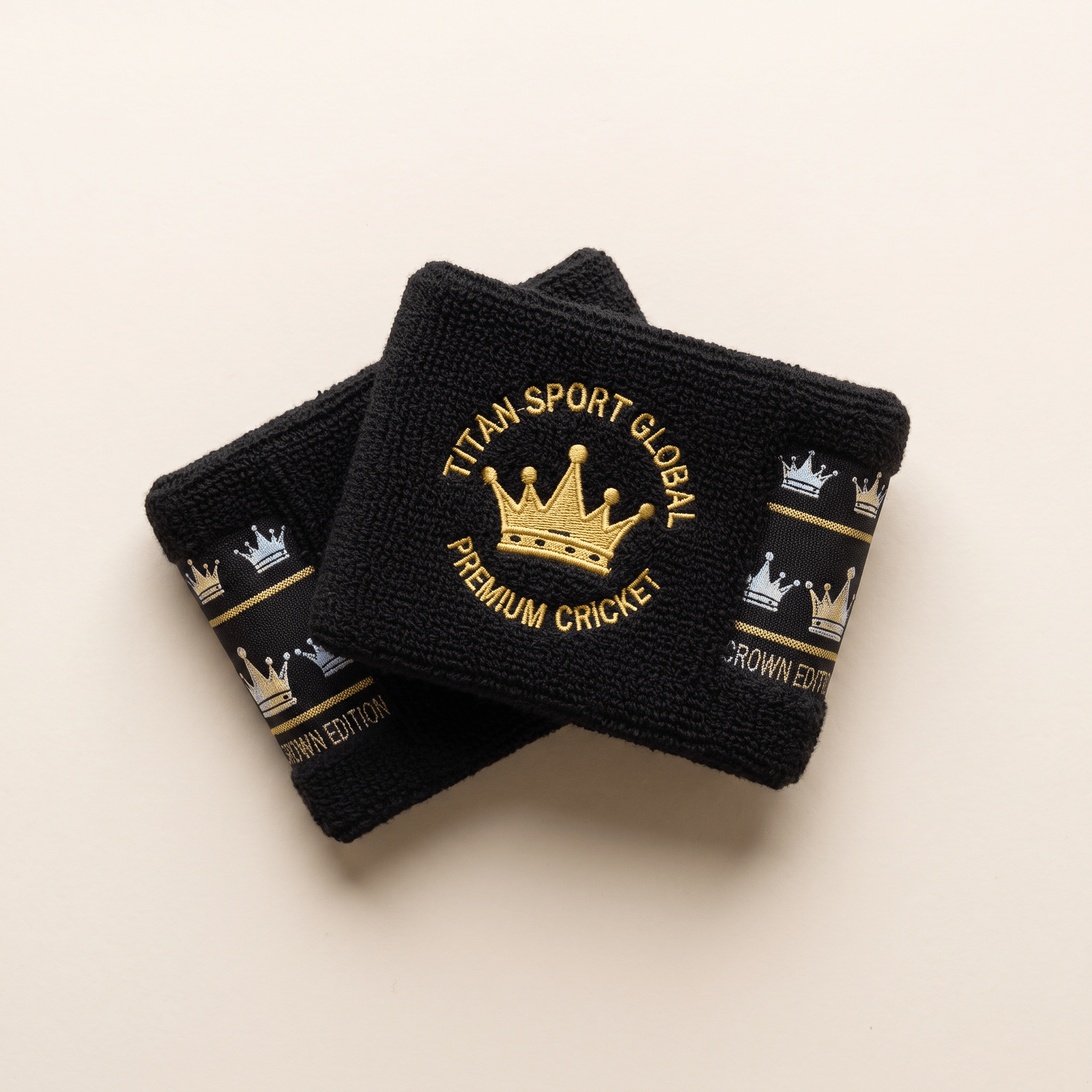 Two black athletic wristbands featuring gold embroidered Titan Sport Global Premium Cricket crown logos.