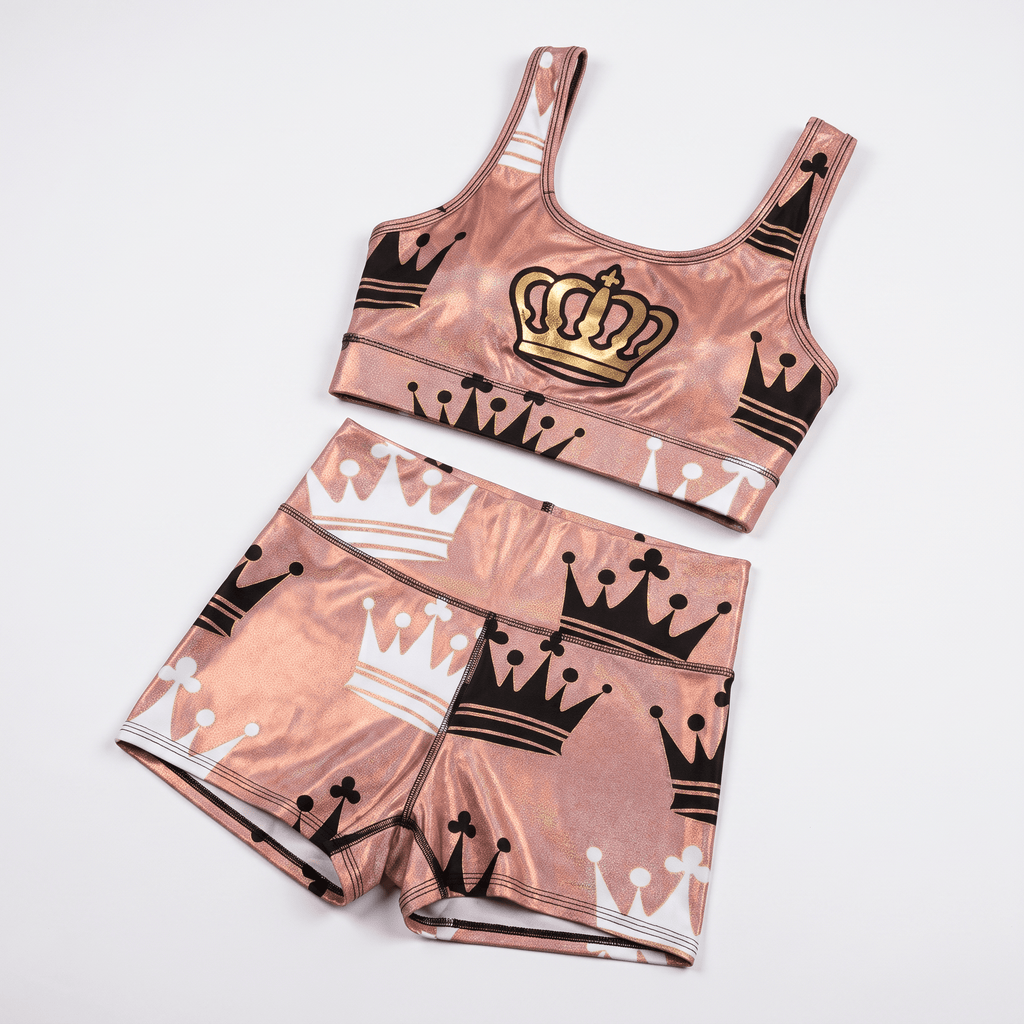 Metallic pink athletic crop top and shorts set featuring black, white, and gold crown prints.