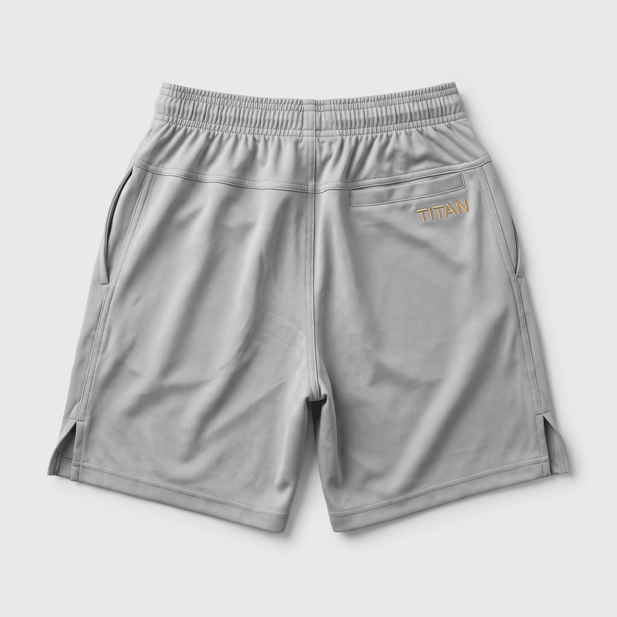Back view of light grey athletic shorts featuring an elastic waistband and gold Titan branding on the rear pocket.