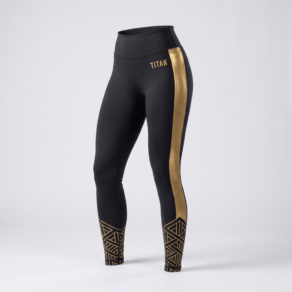 Black high-waisted athletic leggings featuring a metallic gold side stripe, geometric ankle print, and Titan logo.