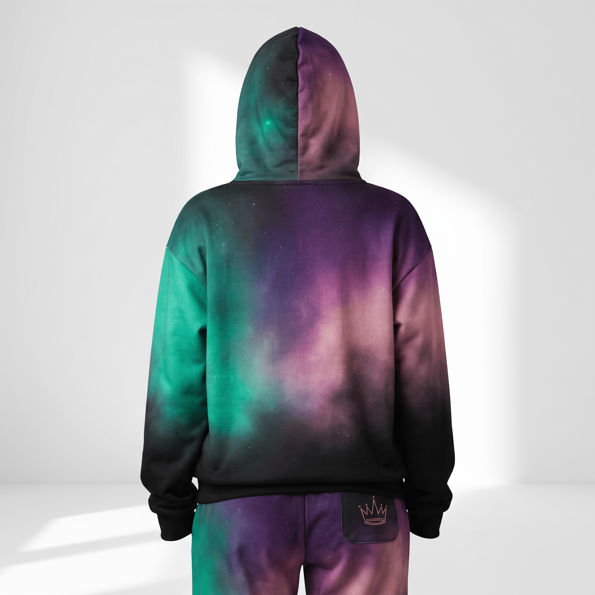 Back view of a person wearing a vibrant nebula print hoodie with green, purple, and black cosmic galaxy pattern.