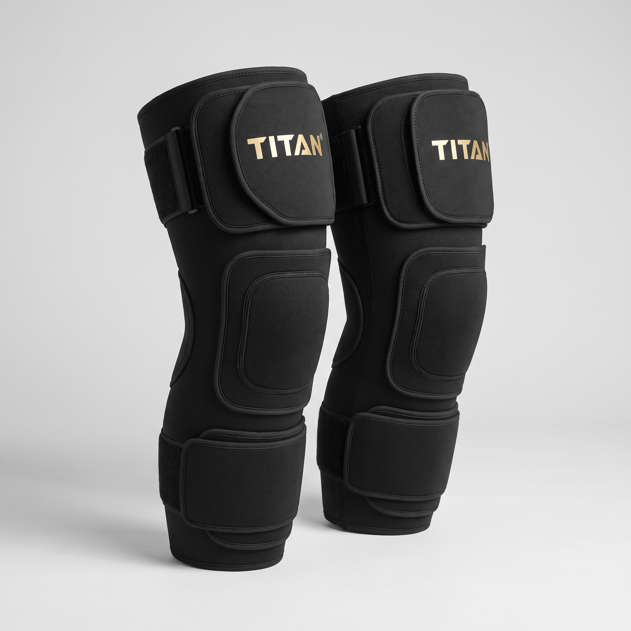 Titan black knee sleeves with gold logo text and adjustable straps displayed on a light background.