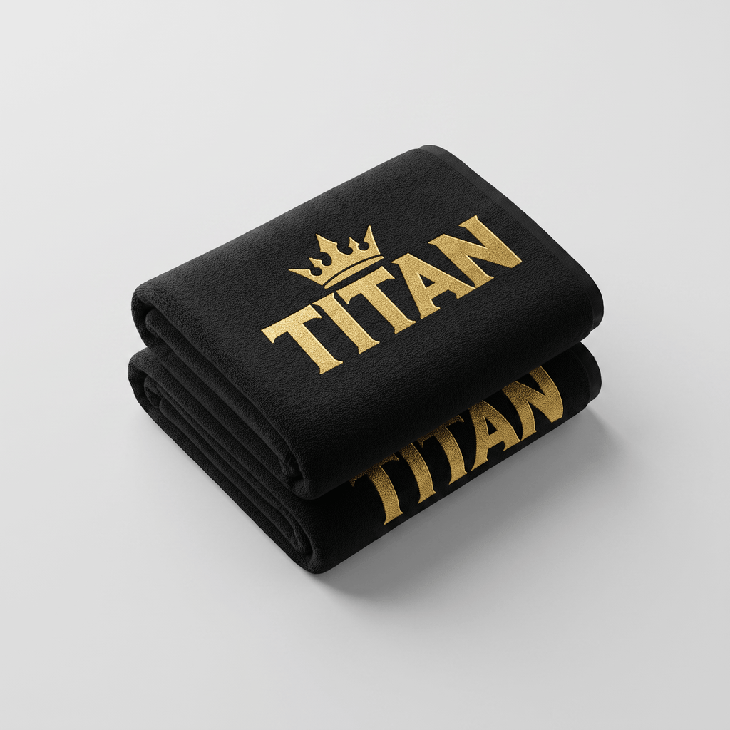 Folded black towel with gold Titan text and crown logo on a white surface.