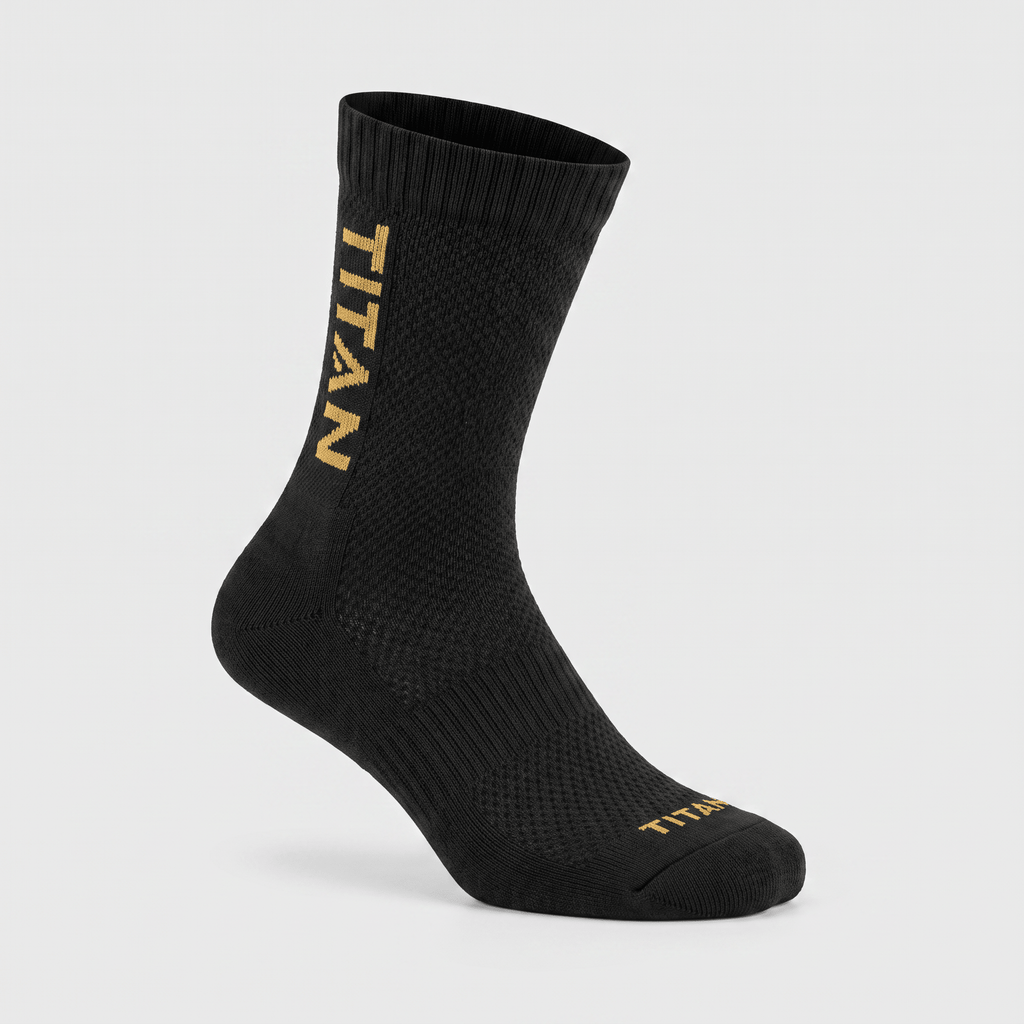 Black athletic crew sock with gold Titan logo on the side and toe against a light gray background.