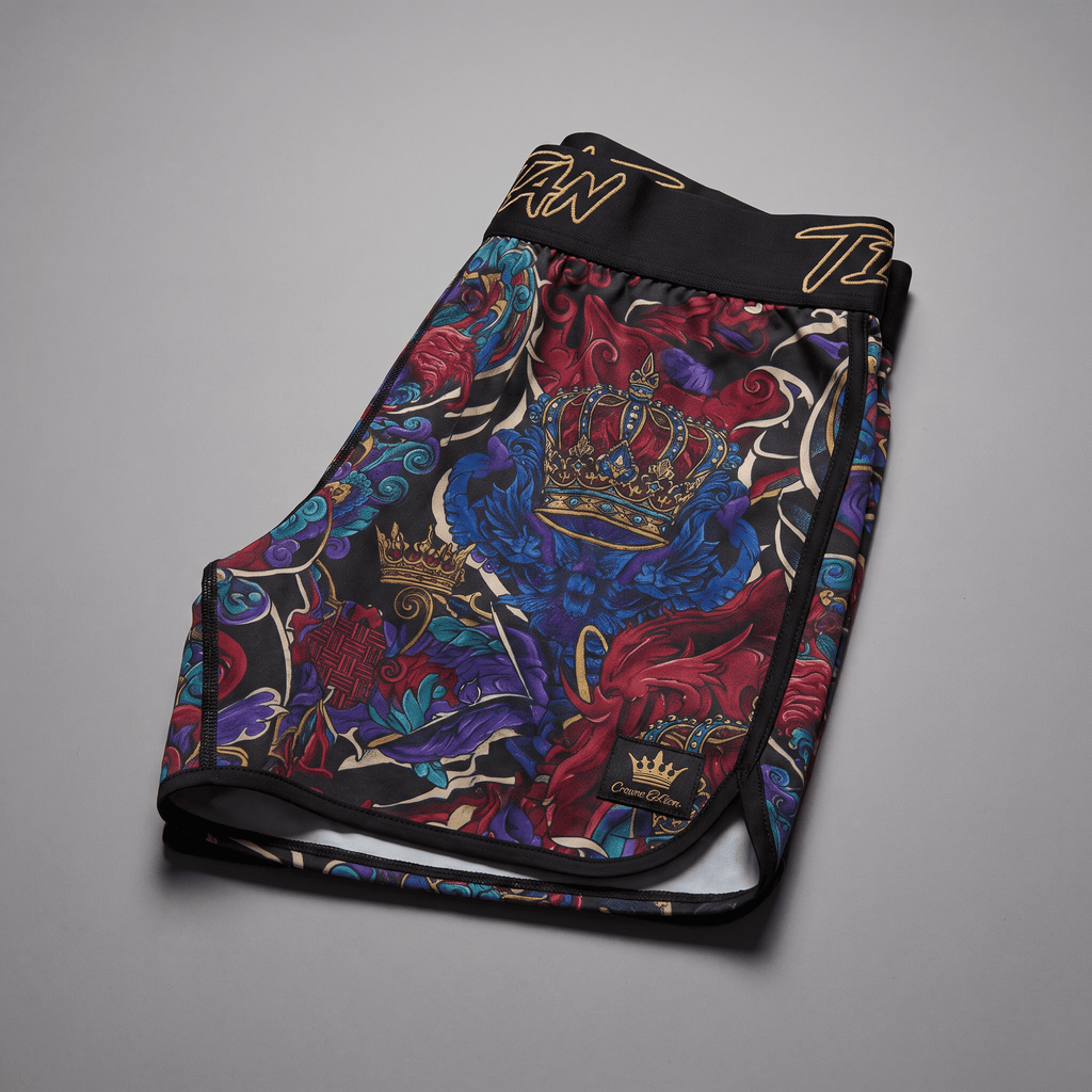 Black athletic shorts with vibrant red, blue, and gold crown tattoo print, wide waistband, and branded label.