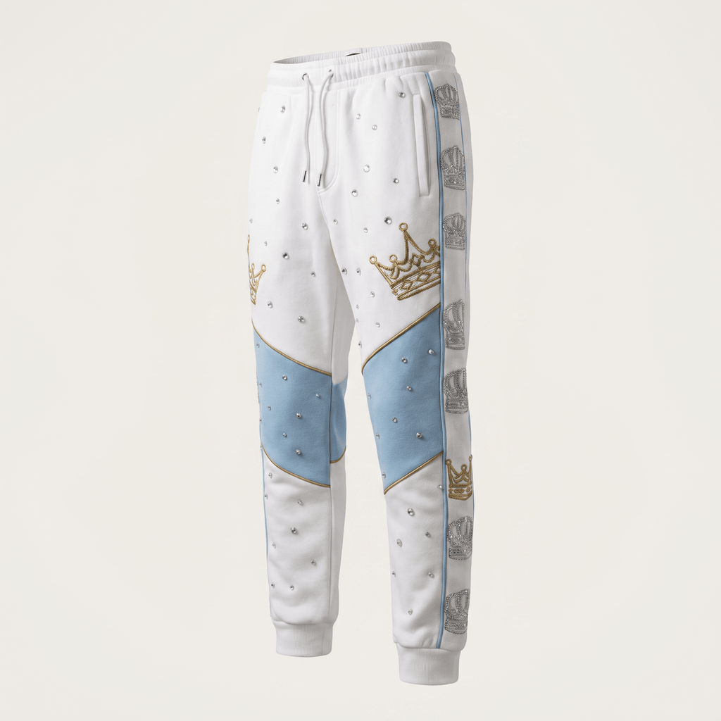 White sweatpants with light blue knee panels, gold crowns, and rhinestone accents on a light background.