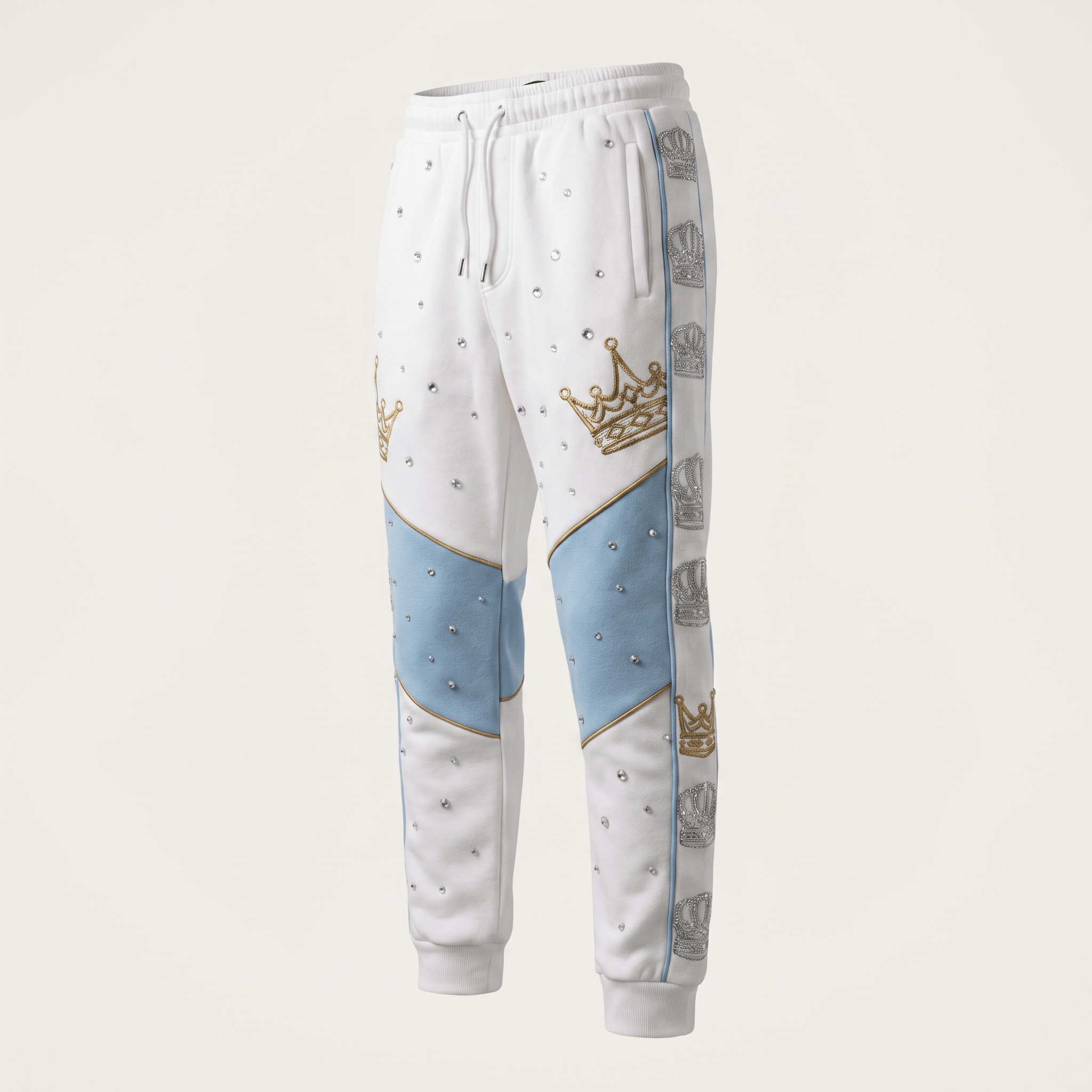 White sweatpants with light blue knee panels, gold crowns, and rhinestone accents on a light background.
