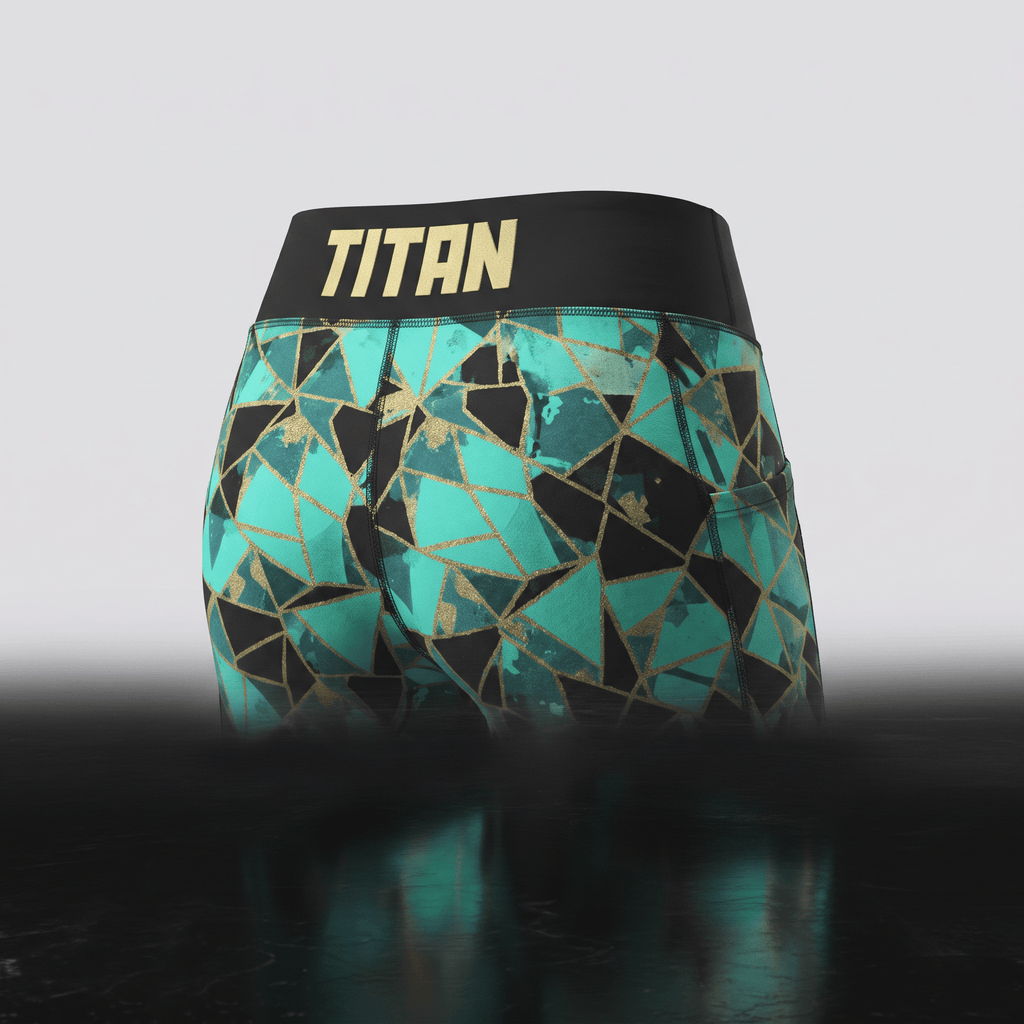 Teal and black geometric print athletic shorts with a wide black waistband featuring the Titan logo in gold.