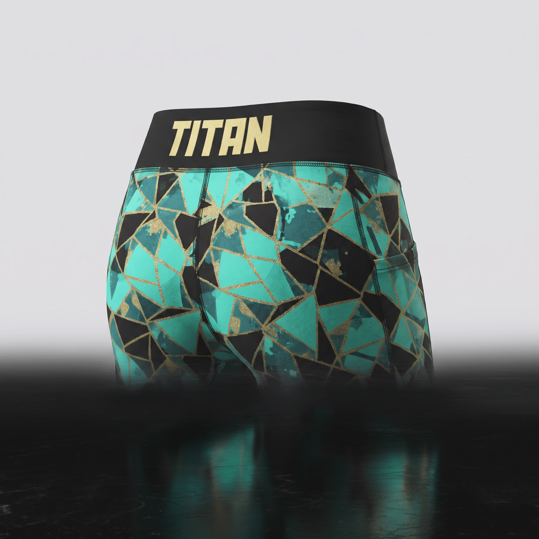 Teal and black geometric print athletic shorts with a wide black waistband featuring the Titan logo in gold.