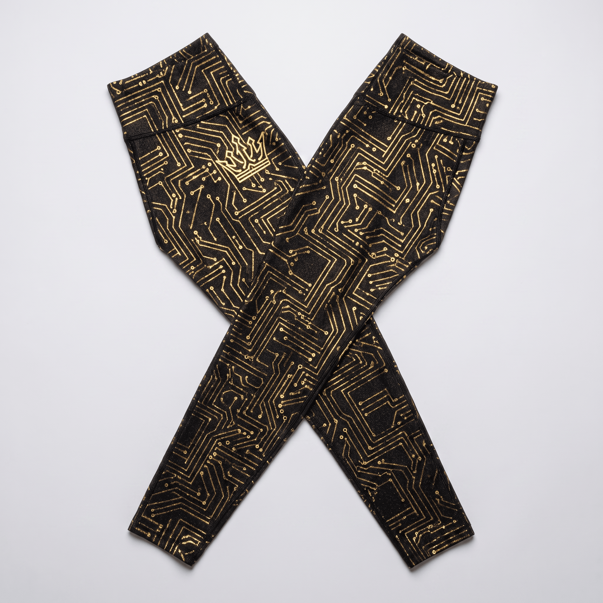 Black leggings with a metallic gold circuit board pattern and crown logo flat laid.
