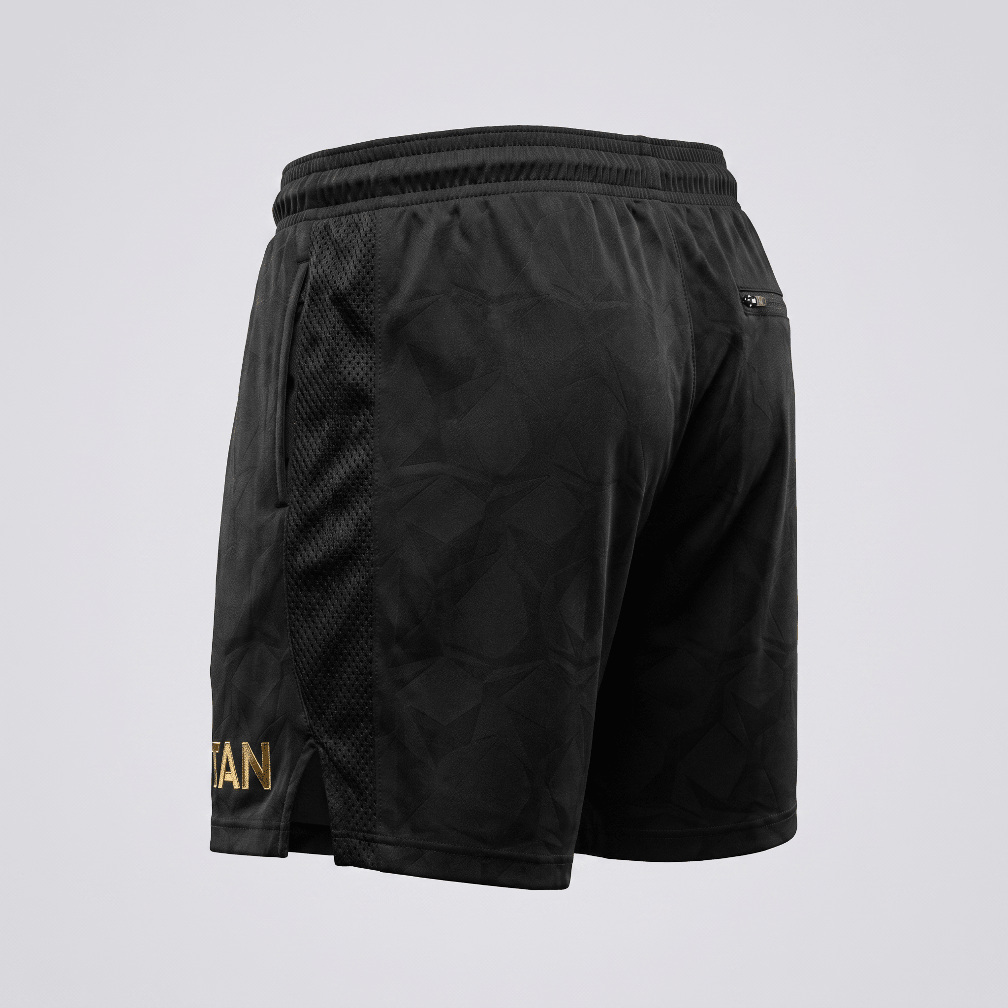 Rear view of black athletic shorts with a subtle geometric pattern, mesh side panels, and gold logo detail.
