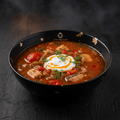 Bulgarian Ribena Chorba in a black bowl with gold accents, topped with sour cream, fresh dill, and red tomatoes.