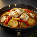 Steaming Portuguese Caldeirada fish stew with potatoes, tomatoes, and peppers in a black bowl with gold leaf accents.