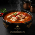 Steaming Serbian fish stew in a black bowl with gold accents, topped with chili, onions, and herbs. Dark background.