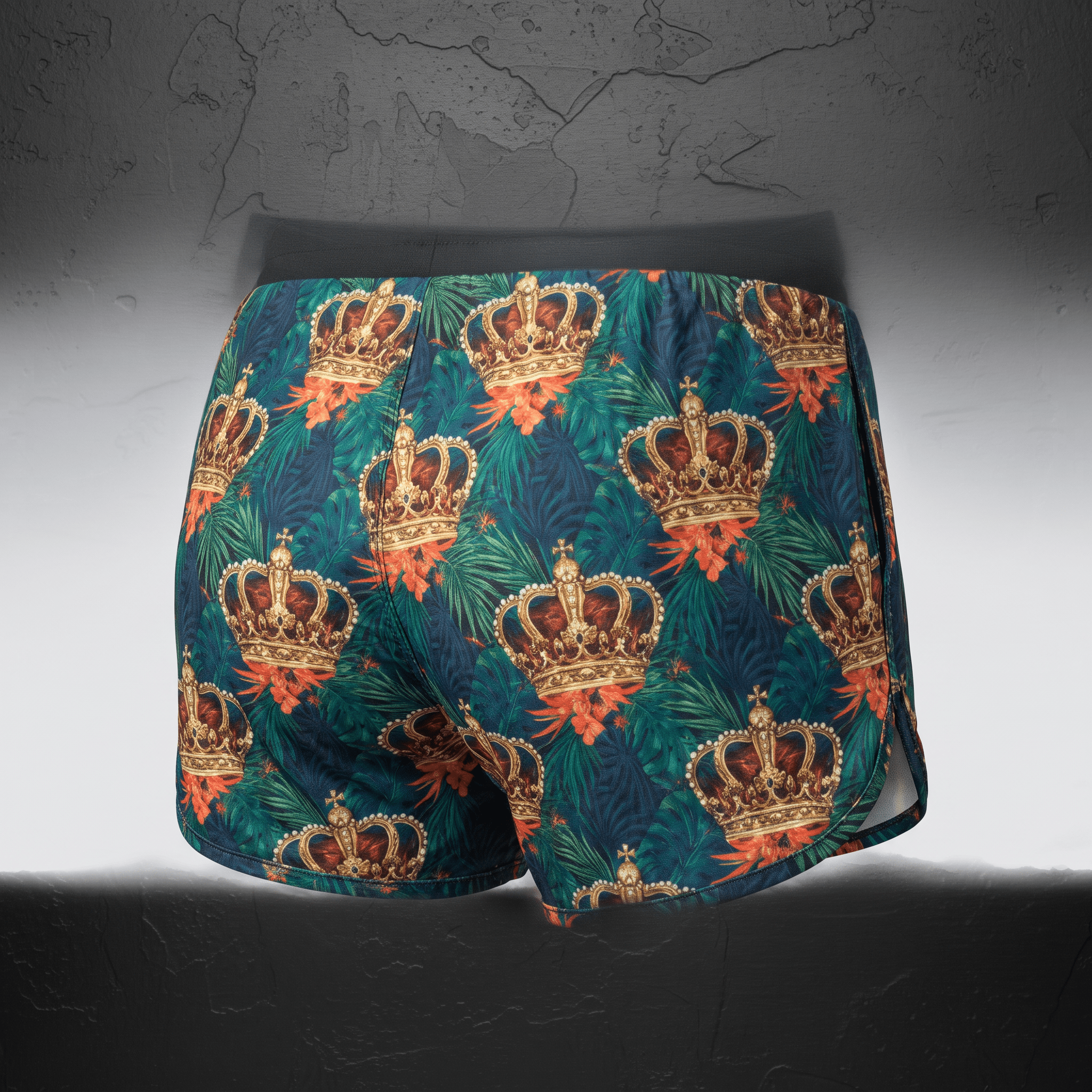 Back view of dark green athletic shorts featuring a tropical crown and flower pattern against a textured grey backdrop.