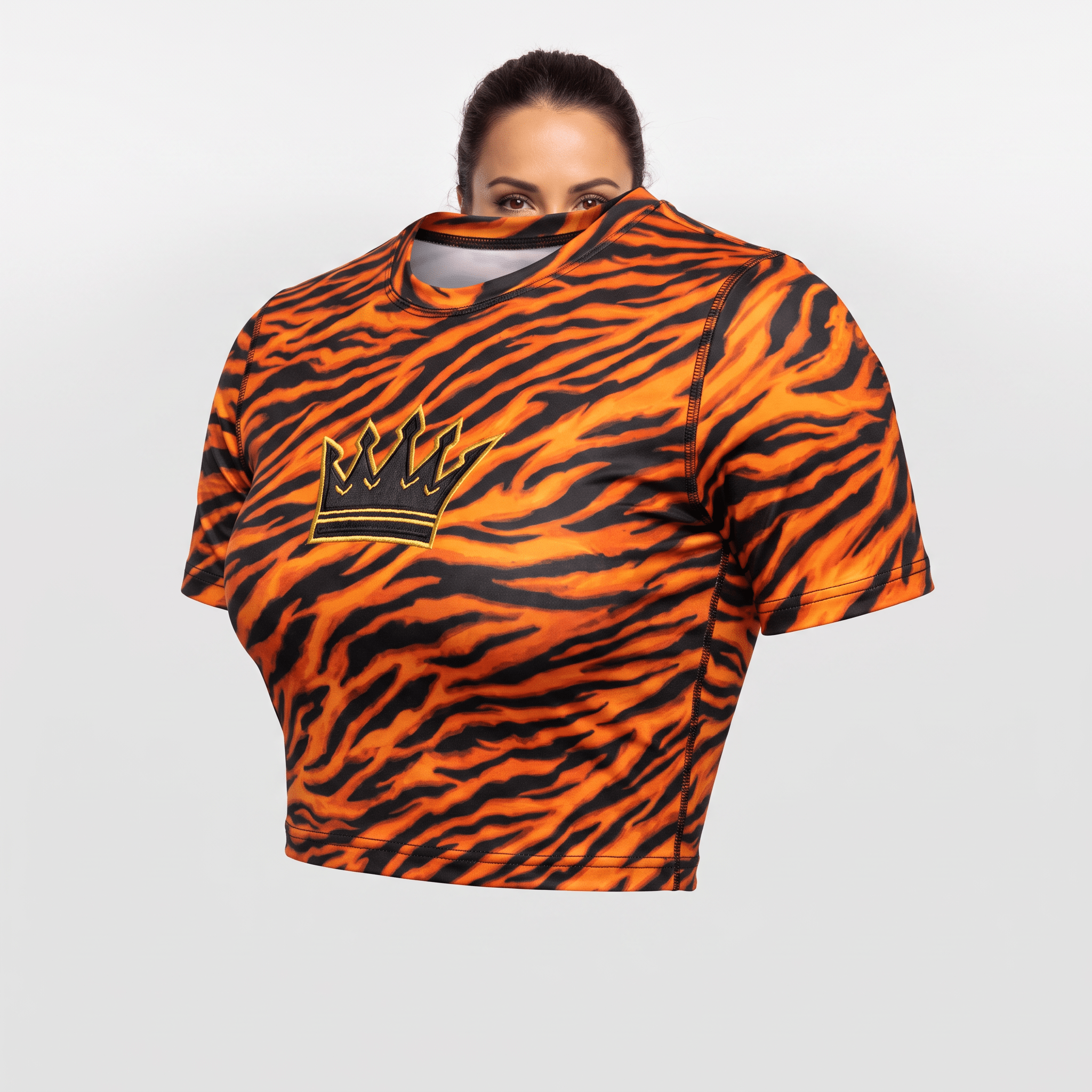 Orange and black tiger stripe crop top with a crown logo, worn by a woman peeking over the neckline.