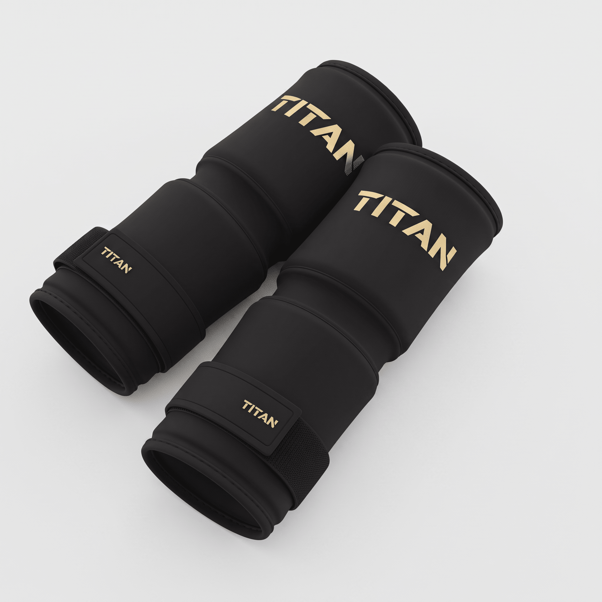 Two black Titan knee sleeves with gold branding on a light background.