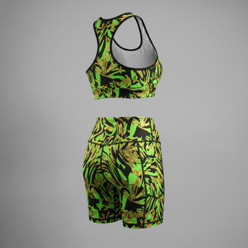 Back view of green and black athletic crop top and biker shorts set with a gold leaf print pattern.