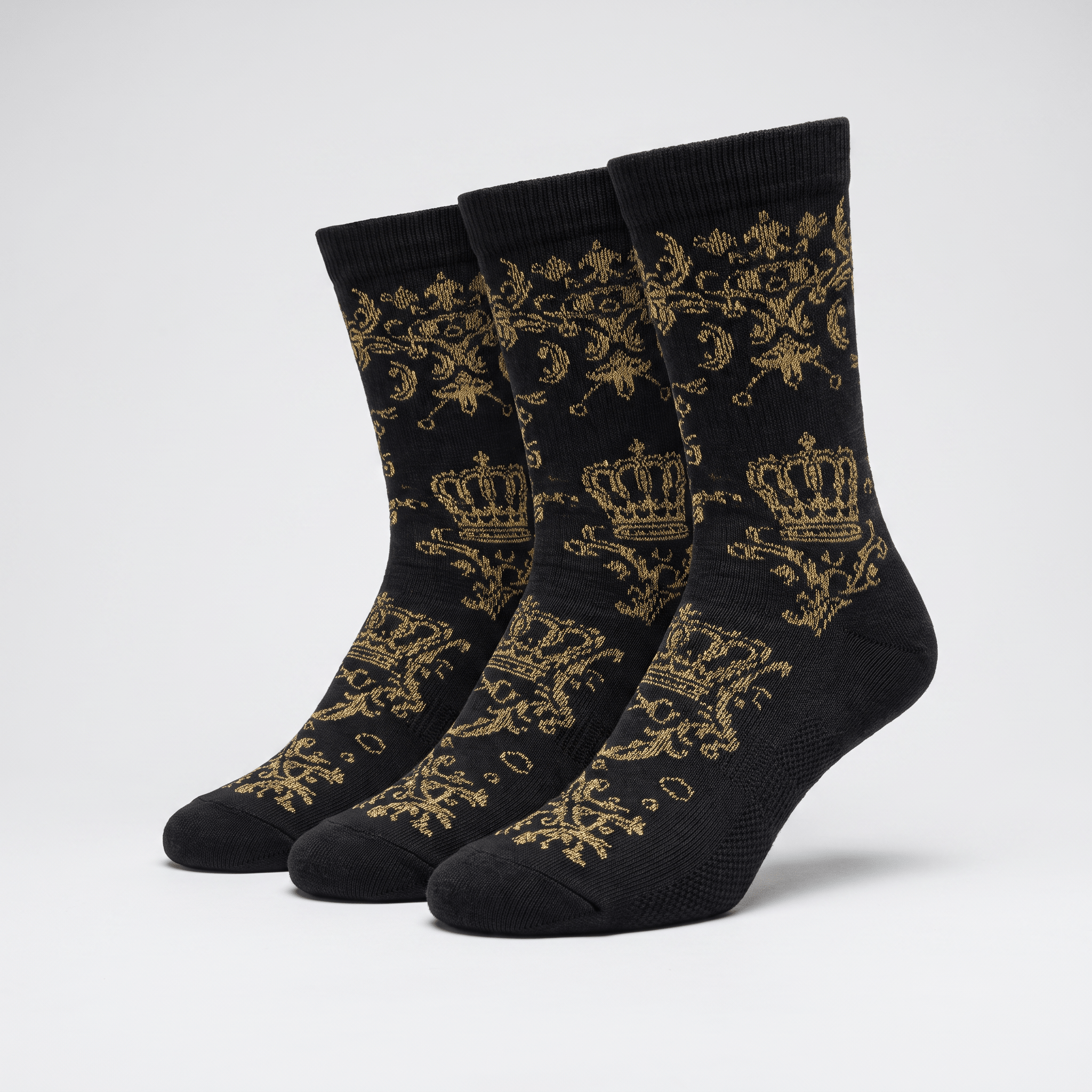 Three black crew socks featuring a gold royal crown and filigree pattern against a light grey background.