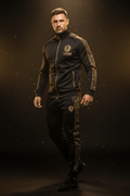Man wears a black track suit with gold lion logo, gold zipper, and geometric gold sleeve and leg paneling.