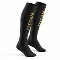 Pair of black compression socks with hexagonal side patterns and vertical gold TITAN branding on white background.