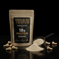 TITAN Organic Cashew Protein pouch, 18g protein label, black scoop with powder, scattered cashews on black background.