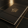 Black folding gymnastics mat with a gold crown logo on a matching black marble floor with gold inlay lines.