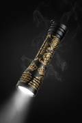 TITAN Crown Edition torch in matte black with gold crown and lion filigree patterns, emitting a bright LED beam.